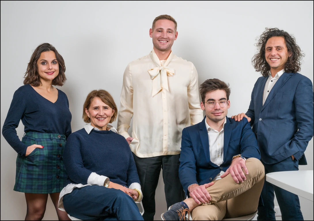 Photo d’Aurélien et de son équipe professionnelle souriant devant un fond neutre dans un cadre de bureau