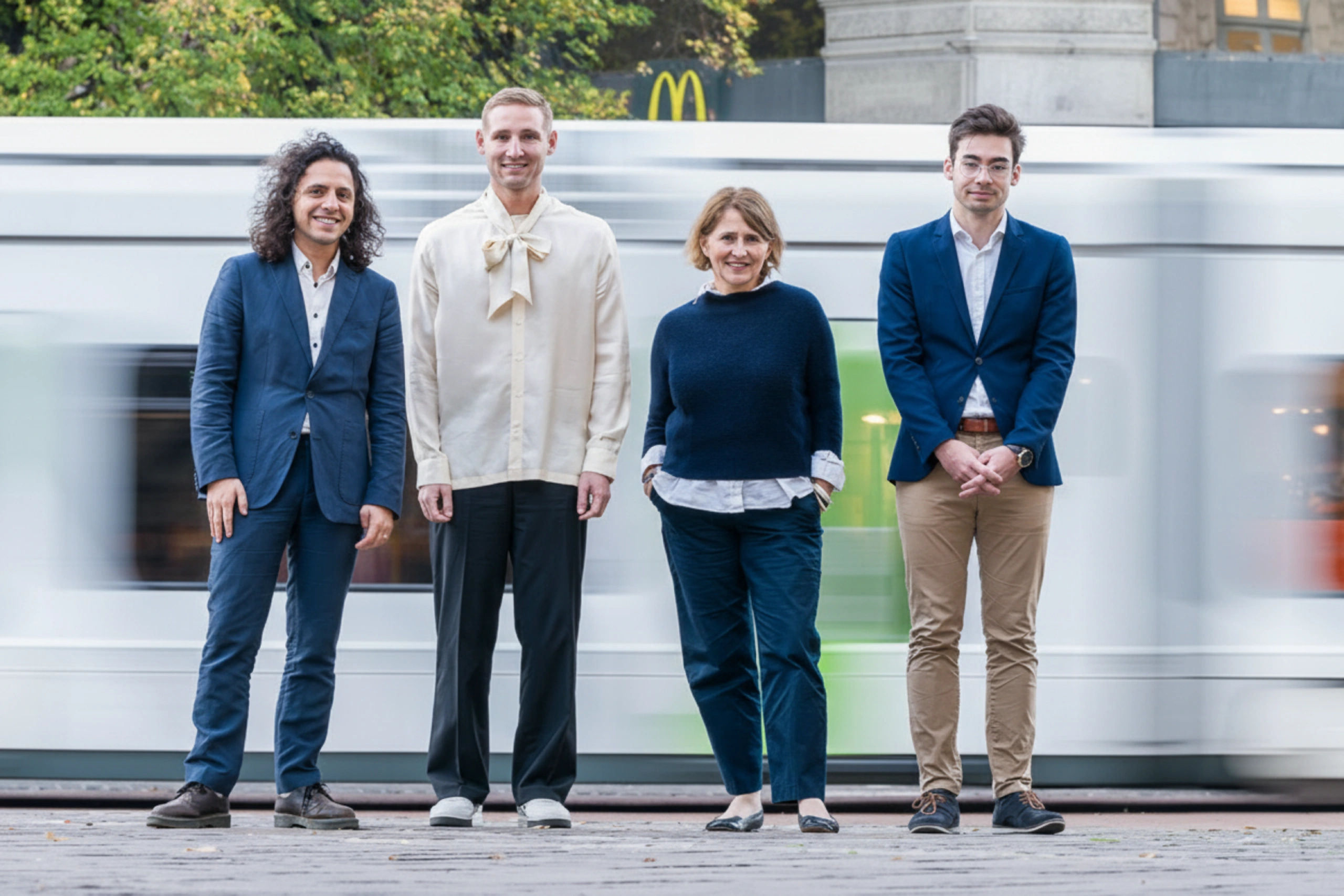Photo de l’équipe professionnelle d’Aurélien marchant ensemble dans un environnement urbain, souriants et en tenue formelle